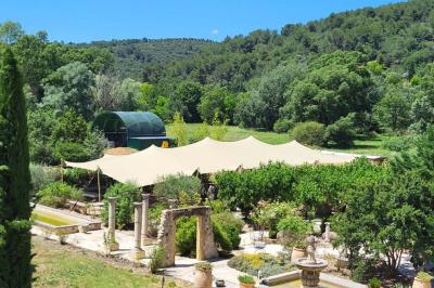 Statue en pierre représentant une femme dans un jardin avec des pots en terre cuite et une allée pavée en arrière-plan.