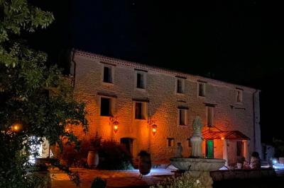 Statue en pierre représentant une femme dans un jardin avec des pots en terre cuite et une allée pavée en arrière-plan.