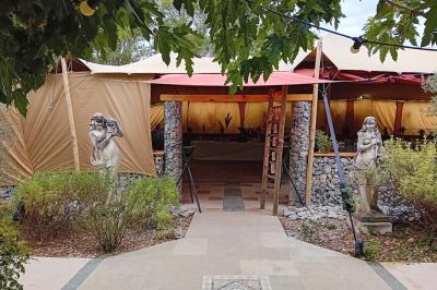 Statue en pierre représentant une femme dans un jardin avec des pots en terre cuite et une allée pavée en arrière-plan.