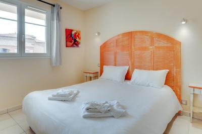 Salon lumineux avec canapé en cuir brun, table basse et accès à un balcon meublé donnant sur un paysage verdoyant.