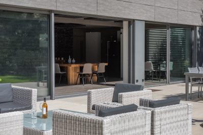 Table dressée pour un dîner en extérieur sous une structure lumineuse avec guirlandes, près d'un bâtiment moderne.