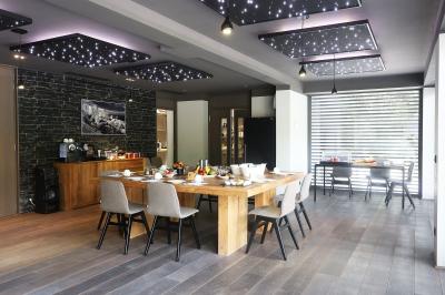 Table dressée pour un dîner en extérieur sous une structure lumineuse avec guirlandes, près d'un bâtiment moderne.
