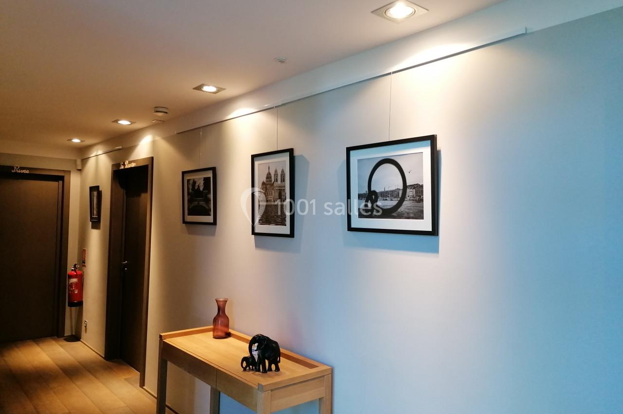 Couloir décoré avec des cadres photo en noir et blanc accrochés au mur, une table en bois et des objets décoratifs.