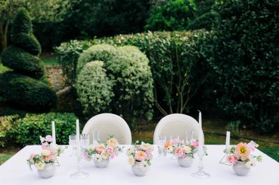 Table dressée pour un dîner en extérieur sous une structure lumineuse avec guirlandes, près d'un bâtiment moderne.
