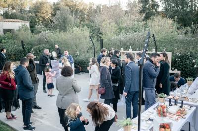 Table dressée pour un dîner en extérieur sous une structure lumineuse avec guirlandes, près d'un bâtiment moderne.