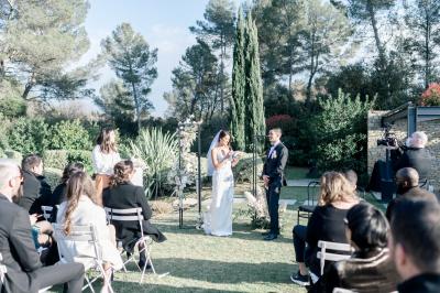 Table dressée pour un dîner en extérieur sous une structure lumineuse avec guirlandes, près d'un bâtiment moderne.