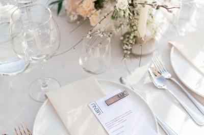 Table dressée pour un dîner en extérieur sous une structure lumineuse avec guirlandes, près d'un bâtiment moderne.