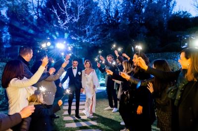 Table dressée pour un dîner en extérieur sous une structure lumineuse avec guirlandes, près d'un bâtiment moderne.