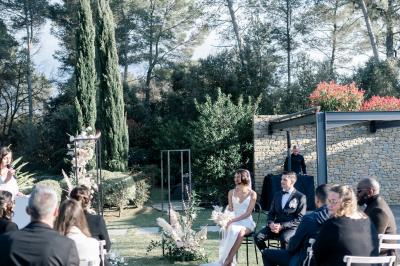 Table dressée pour un dîner en extérieur sous une structure lumineuse avec guirlandes, près d'un bâtiment moderne.