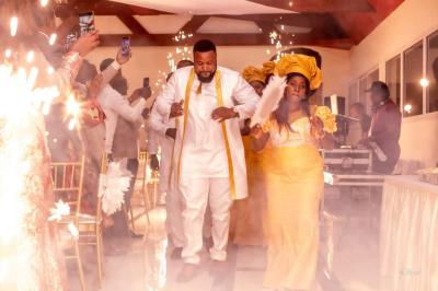 Des personnes dansent dans une salle éclairée par des projecteurs, ambiance festive avec des invités en arrière-plan.