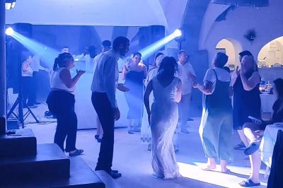 Des personnes dansent dans une salle éclairée par des projecteurs, ambiance festive avec des invités en arrière-plan.