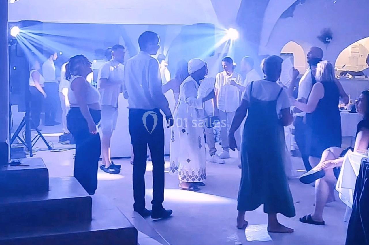 Des personnes dansent et discutent dans une salle éclairée par des projecteurs lumineux lors d'un événement festif.