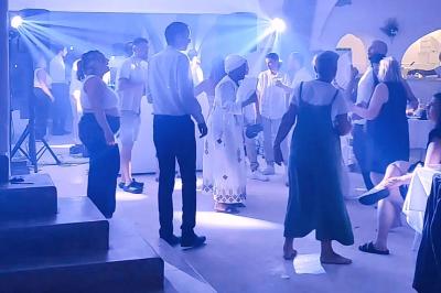 Personnes dansant dans une salle éclairée par des projecteurs bleus, ambiance festive et décontractée.