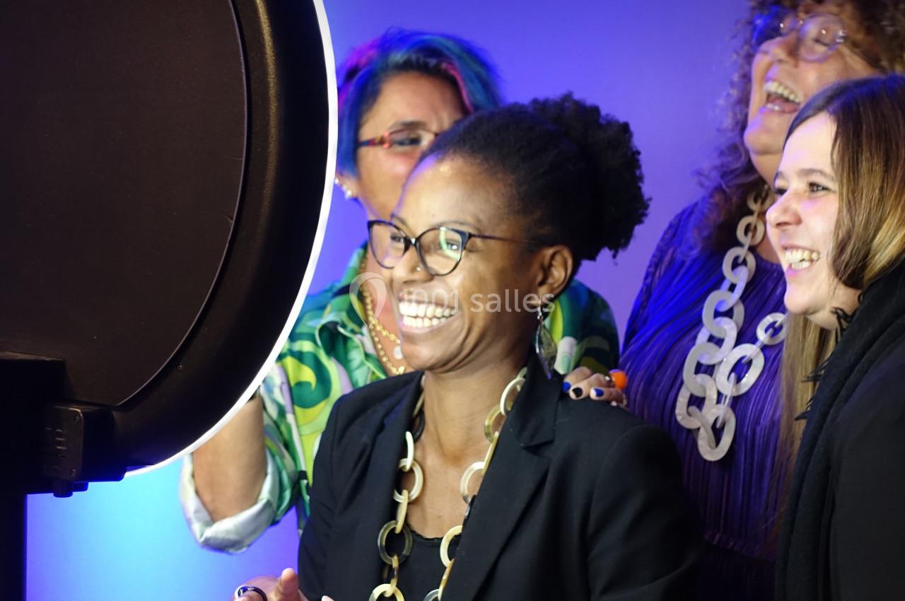 Quatre personnes souriantes posent devant un éclairage circulaire dans un environnement lumineux.