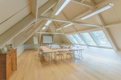 Chambre lumineuse avec lit double, plaid coloré, bureau en bois, chaise et vue sur un jardin par une fenêtre ouverte.