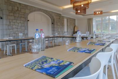 Chambre lumineuse avec lit double, plaid coloré, bureau en bois, chaise et vue sur un jardin par une fenêtre ouverte.