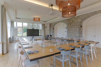 Chambre lumineuse avec lit double, plaid coloré, bureau en bois, chaise et vue sur un jardin par une fenêtre ouverte.