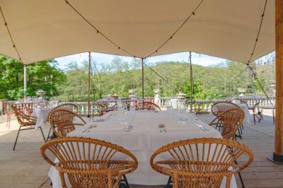 Chambre lumineuse avec lit double, plaid coloré, bureau en bois, chaise et vue sur un jardin par une fenêtre ouverte.