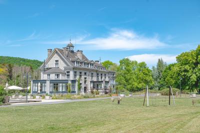 Chambre lumineuse avec lit double, plaid coloré, bureau en bois, chaise et vue sur un jardin par une fenêtre ouverte.
