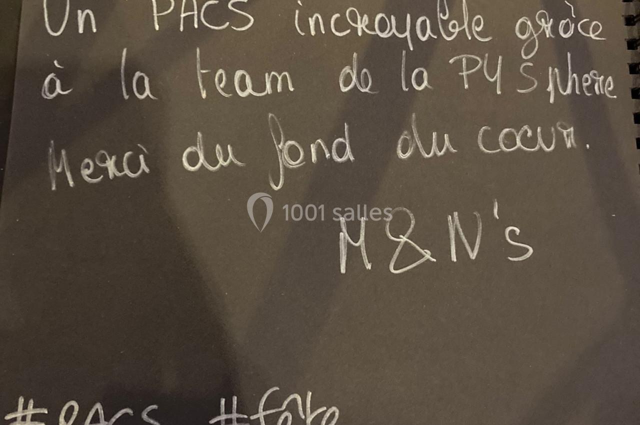 Carte noire manuscrite avec un message de remerciement pour une célébration de PACS, posée sur une table.