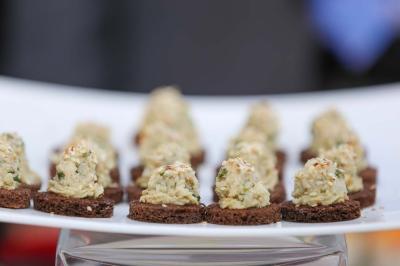 Table ronde avec verres vides, assiettes empilées, couverts, serviettes et desserts en arrière-plan.