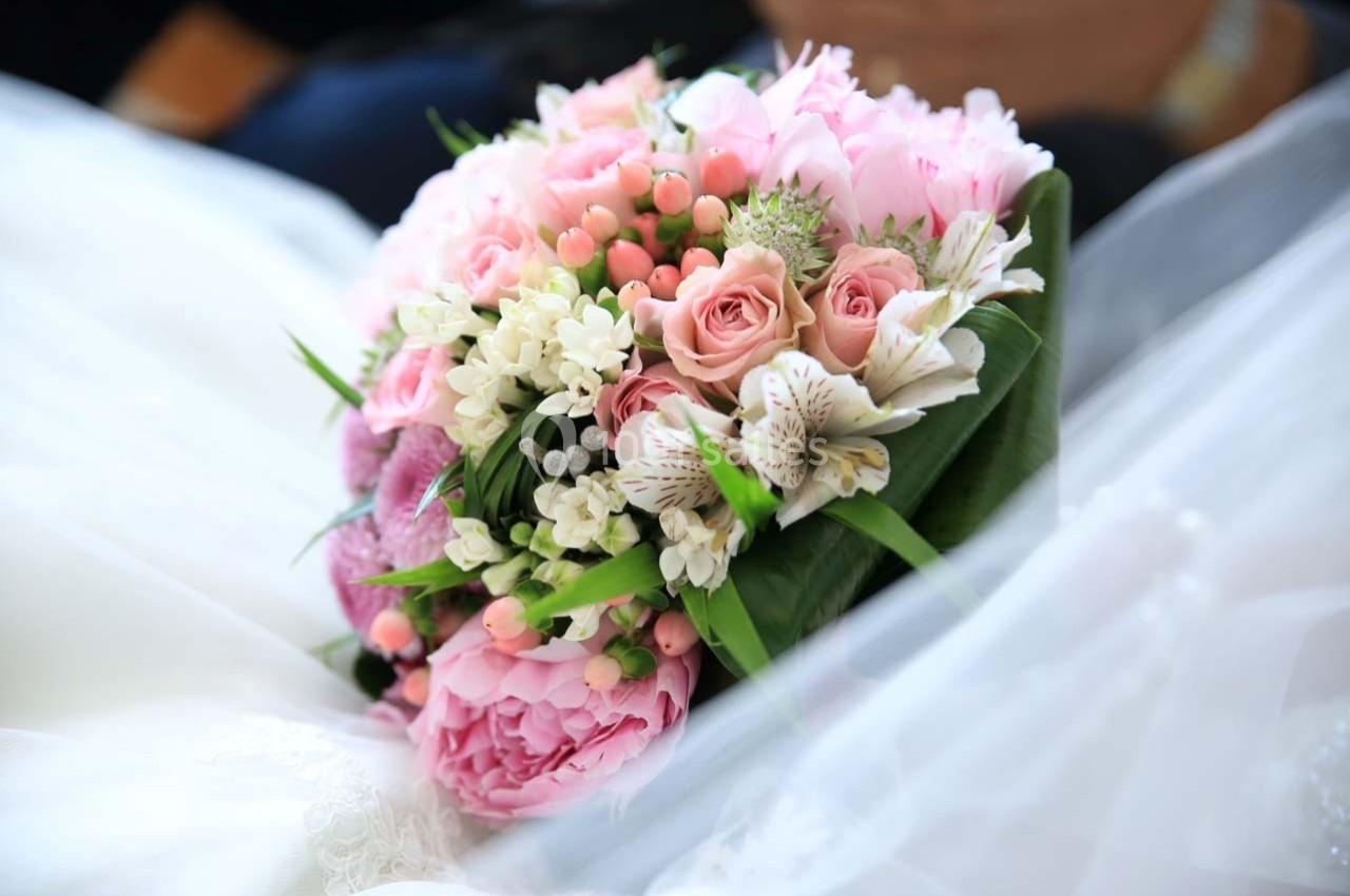 Bouquet de fleurs roses et blanches avec des feuillages verts, posé sur un tissu blanc.