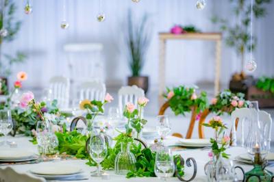 Table ronde avec verres vides, assiettes empilées, couverts, serviettes et desserts en arrière-plan.