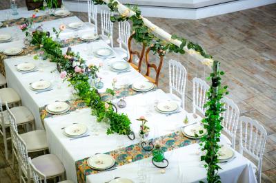 Table ronde avec verres vides, assiettes empilées, couverts, serviettes et desserts en arrière-plan.