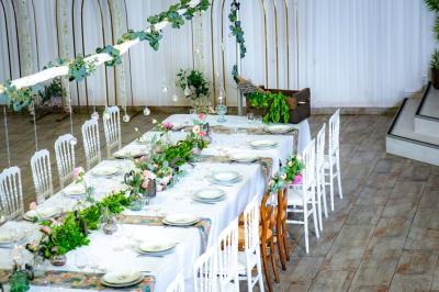 Table ronde avec verres vides, assiettes empilées, couverts, serviettes et desserts en arrière-plan.
