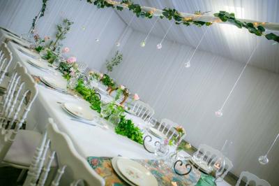 Table ronde avec verres vides, assiettes empilées, couverts, serviettes et desserts en arrière-plan.