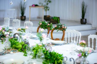 Table ronde avec verres vides, assiettes empilées, couverts, serviettes et desserts en arrière-plan.