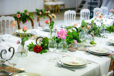 Table ronde avec verres vides, assiettes empilées, couverts, serviettes et desserts en arrière-plan.