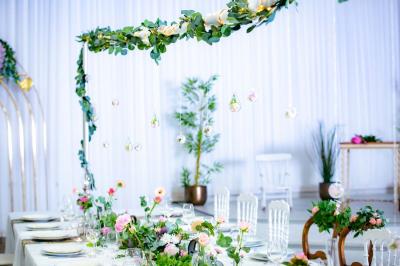 Table ronde avec verres vides, assiettes empilées, couverts, serviettes et desserts en arrière-plan.