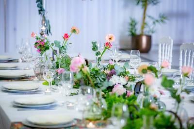 Table ronde avec verres vides, assiettes empilées, couverts, serviettes et desserts en arrière-plan.