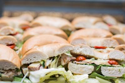 Table ronde avec verres vides, assiettes empilées, couverts, serviettes et desserts en arrière-plan.