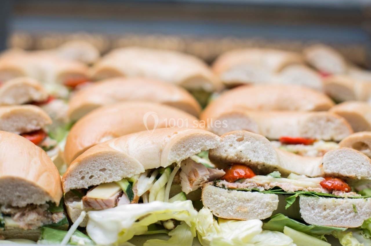 Bagels garnis de légumes, fromage et viande, disposés en rangées sur un plateau.