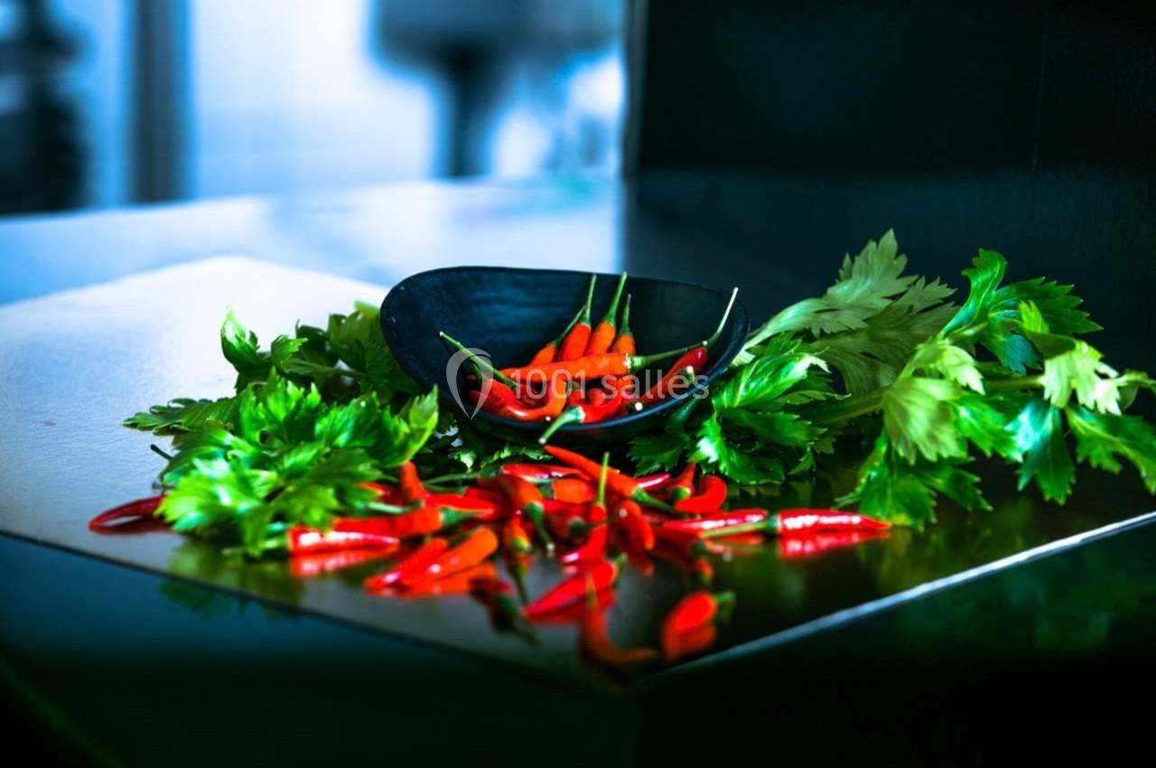 Piments rouges dans un bol noir entouré de feuilles de persil frais sur une surface sombre.