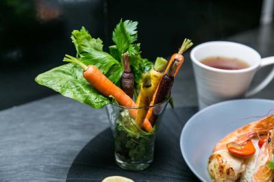 Table ronde avec verres vides, assiettes empilées, couverts, serviettes et desserts en arrière-plan.