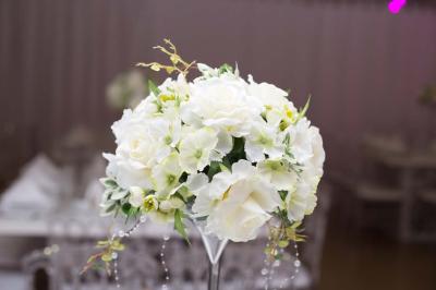 Table ronde avec verres vides, assiettes empilées, couverts, serviettes et desserts en arrière-plan.