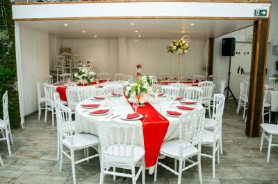Table ronde avec verres vides, assiettes empilées, couverts, serviettes et desserts en arrière-plan.