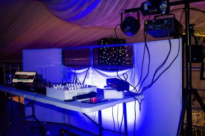 Table ronde avec verres vides, assiettes empilées, couverts, serviettes et desserts en arrière-plan.