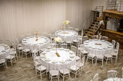 Table ronde avec verres vides, assiettes empilées, couverts, serviettes et desserts en arrière-plan.