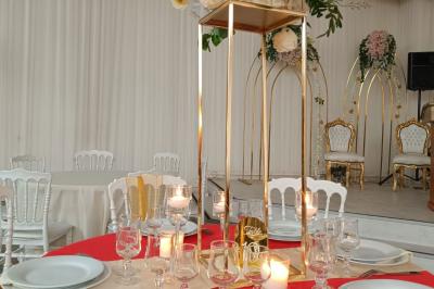 Table ronde avec verres vides, assiettes empilées, couverts, serviettes et desserts en arrière-plan.