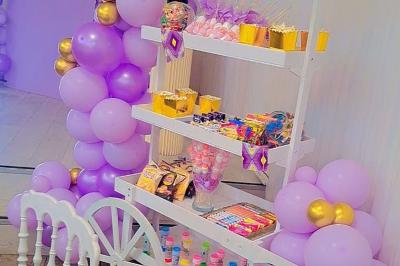 Table ronde avec verres vides, assiettes empilées, couverts, serviettes et desserts en arrière-plan.