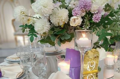 Table ronde avec verres vides, assiettes empilées, couverts, serviettes et desserts en arrière-plan.