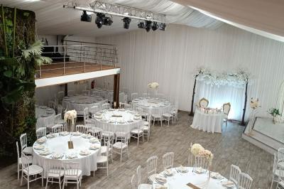 Table ronde avec verres vides, assiettes empilées, couverts, serviettes et desserts en arrière-plan.