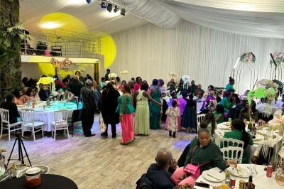 Table ronde avec verres vides, assiettes empilées, couverts, serviettes et desserts en arrière-plan.