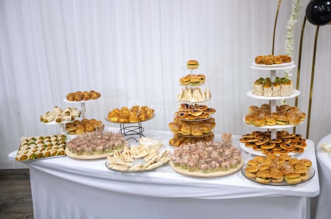 Buffet de pâtisseries et amuse-bouches variés disposés sur des présentoirs et une table blanche.
