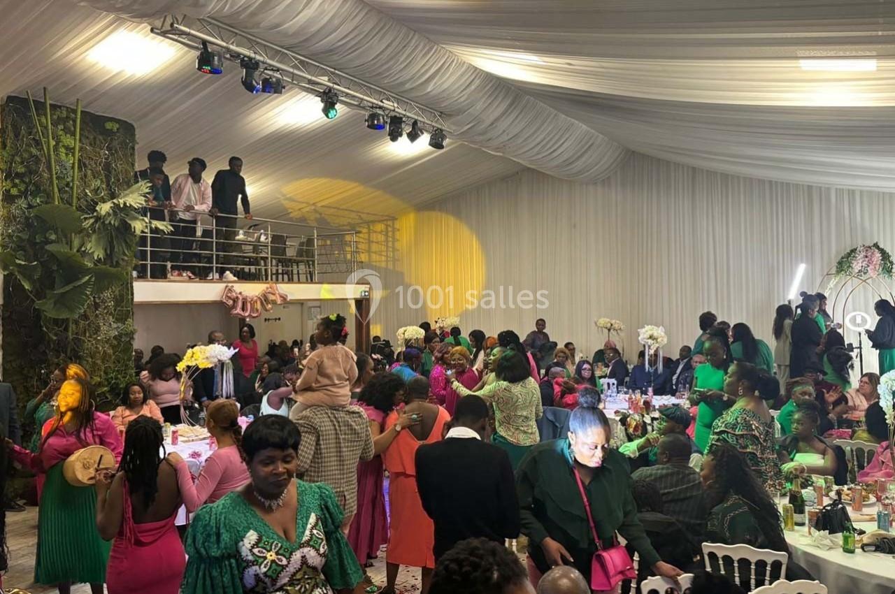 Des invités vêtus de tenues colorées participent à une réception festive dans une salle décorée avec des fleurs et des…