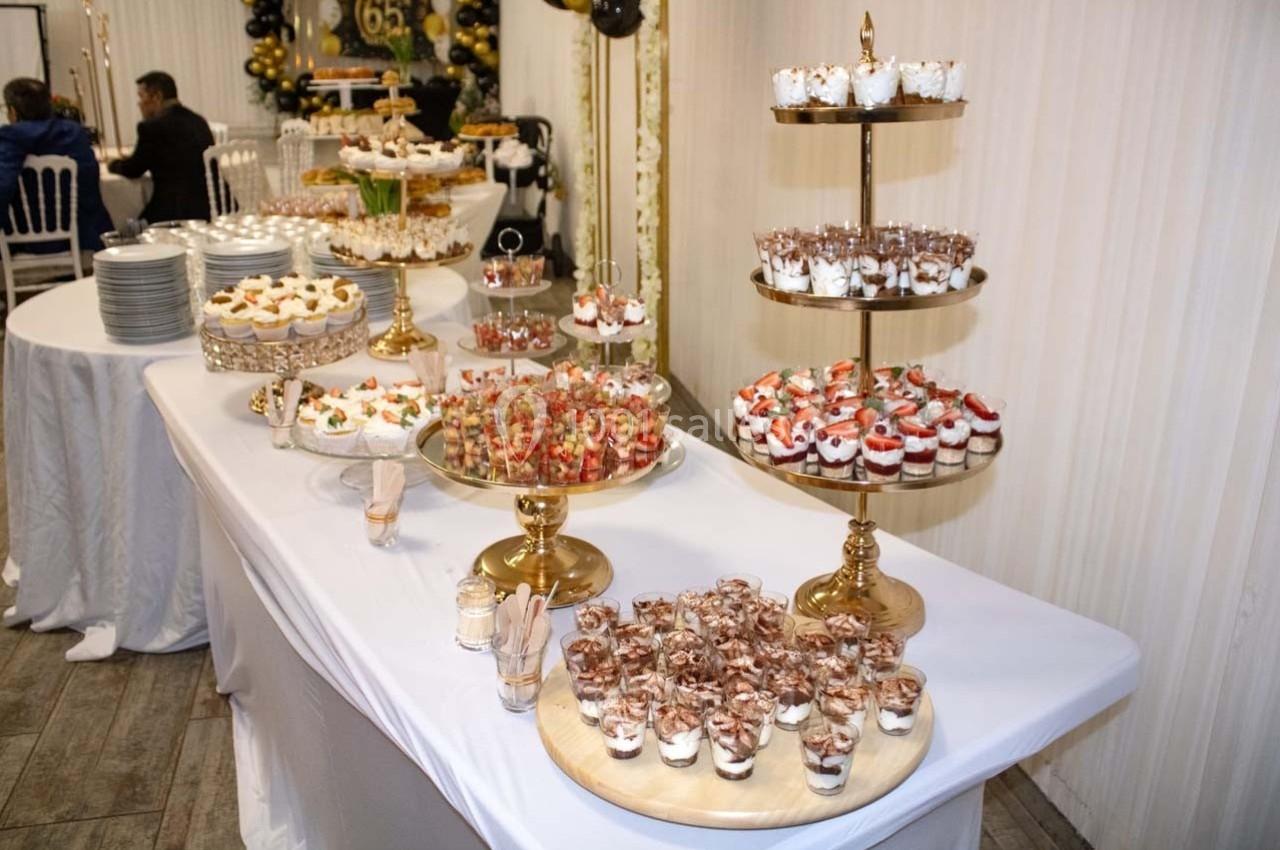 Table dressée avec des desserts variés, dont verrines, gâteaux et pâtisseries, présentés sur des supports dorés.